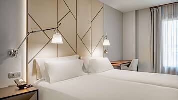 A hotel room with a large bed, two bedside lamps, a desk, and a chair.