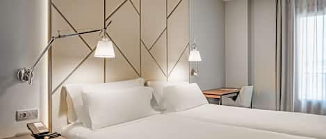 Une chambre d’hôtel avec un grand lit, deux lampes de chevet, un bureau et une chaise.