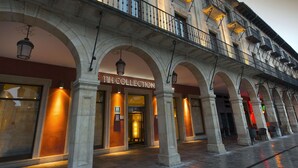 Un edificio con un letrero que dice "1H COLLECTION", entradas arqueadas y un balcón con barandillas.
