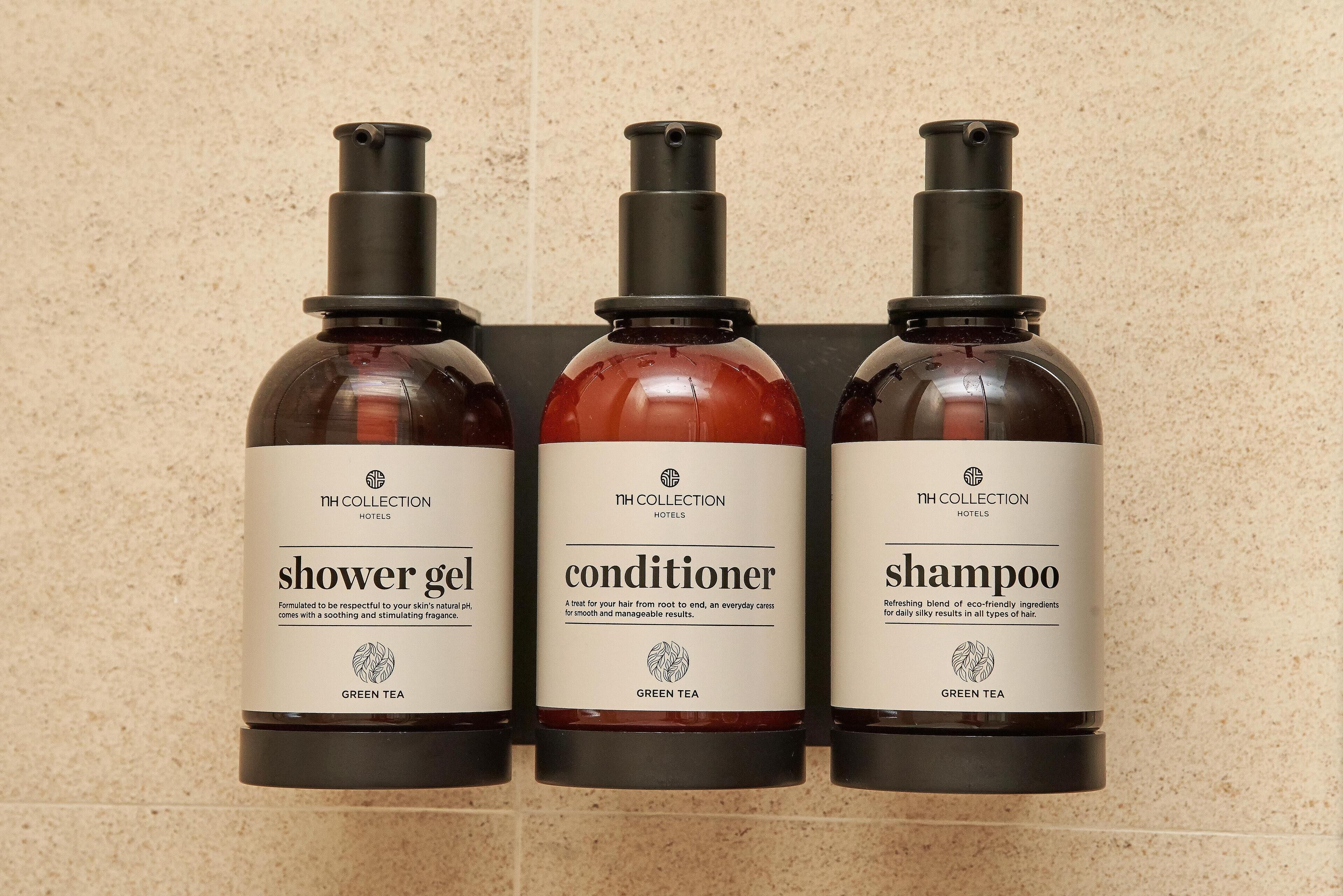 Drei Flaschen Produkte von NH Collection Hotels: Duschgel, Conditioner und Shampoo, alle mit 'GREEN TEA' beschriftet.