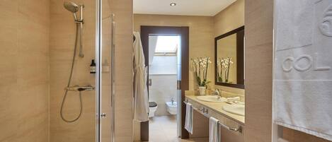 A modern bathroom with a glass-enclosed shower, a vanity with a large mirror, and a towel rack.