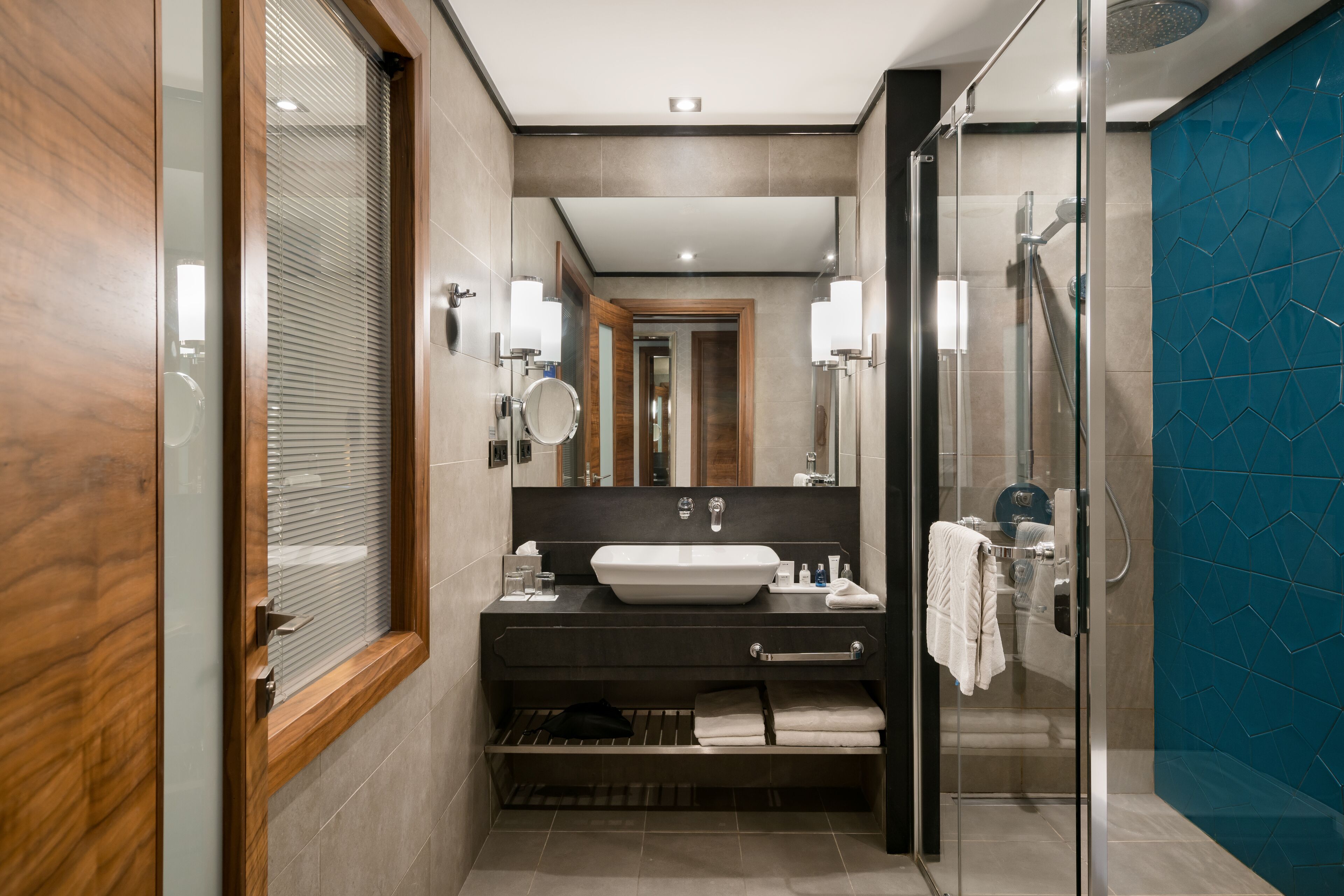 A modern bathroom with a large mirror, a sink, and a glass-enclosed shower.