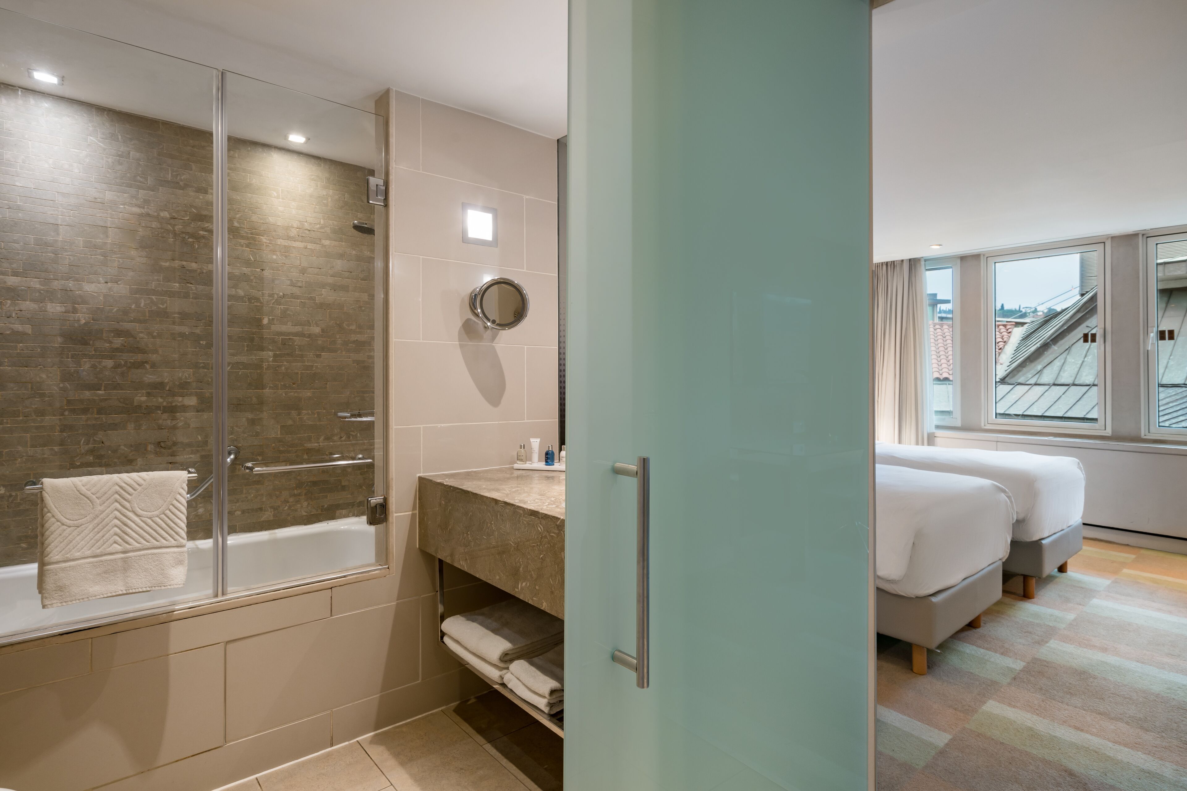 Un baño moderno con cabina de ducha de vidrio, bañera y tocador con espejo.
