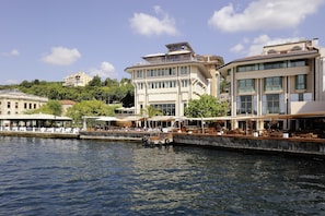 A waterfront hotel with a dining area overlooking the water, a covered outdoor seating area, and a large building with multiple floors and balconies. - Radisson Blu Bosphorus Hotel, Istanbul (Istanbul)