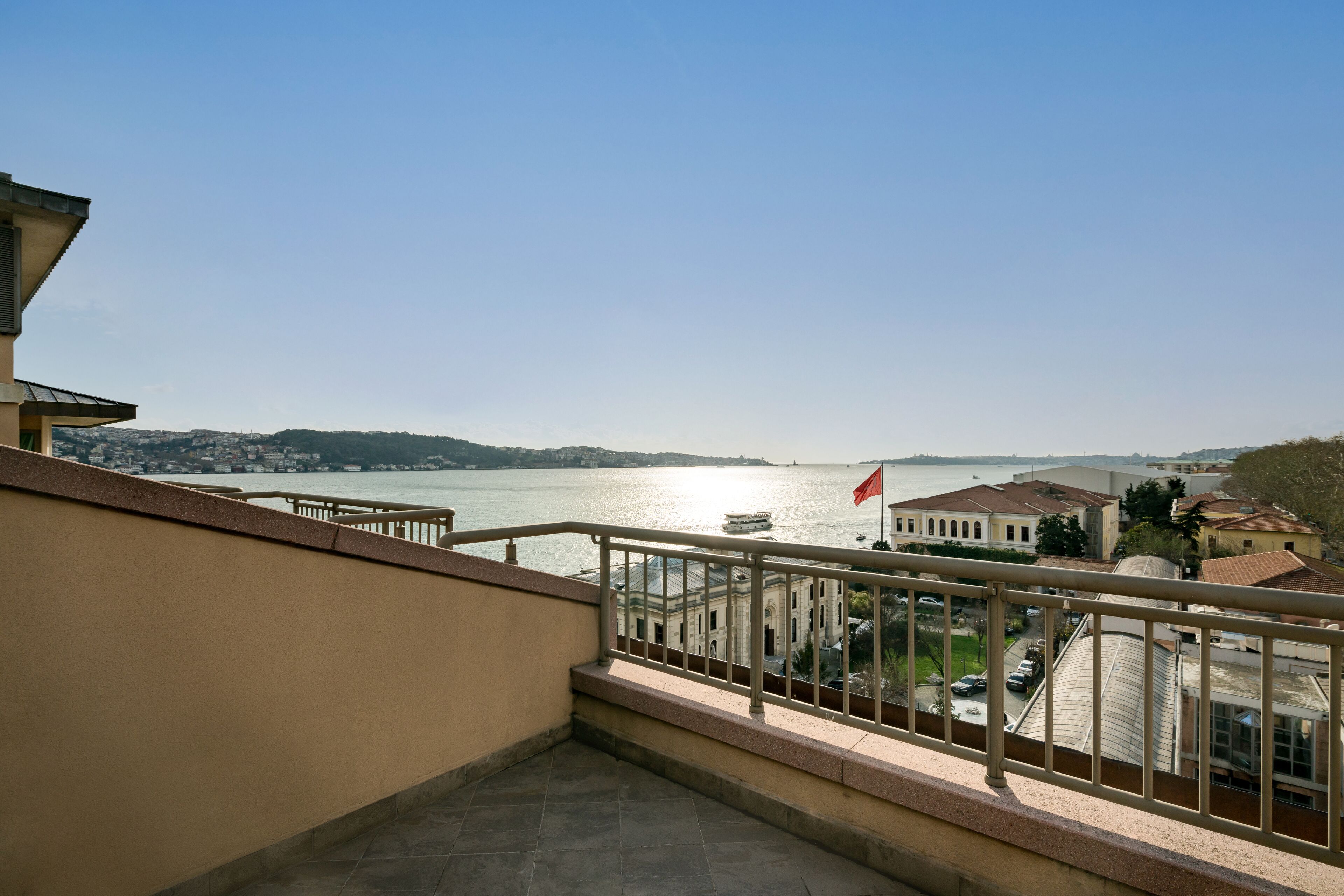 A balcony with a view of a river and buildings across it.