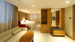 A hotel room with a bed, a sofa, a desk, and a TV.