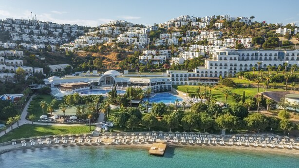 Un complexe hôtelier doté d’une piscine, d’une plage et offrant une vue sur les collines.