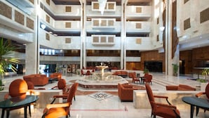 A spacious lobby with a central fountain, multiple seating areas, and a high ceiling with decorative panels. - L´Orient Palace Resort & Spa (Sousse)