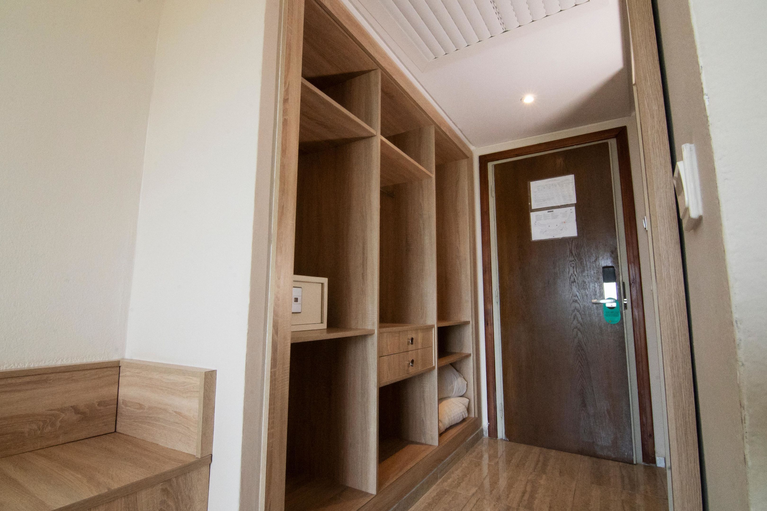 Un pasillo con un armario de madera, una puerta con cerradura y un mueble pequeño.