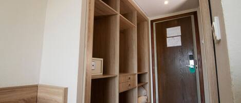 Un pasillo con un armario de madera, una puerta con cerradura y un mueble pequeño.