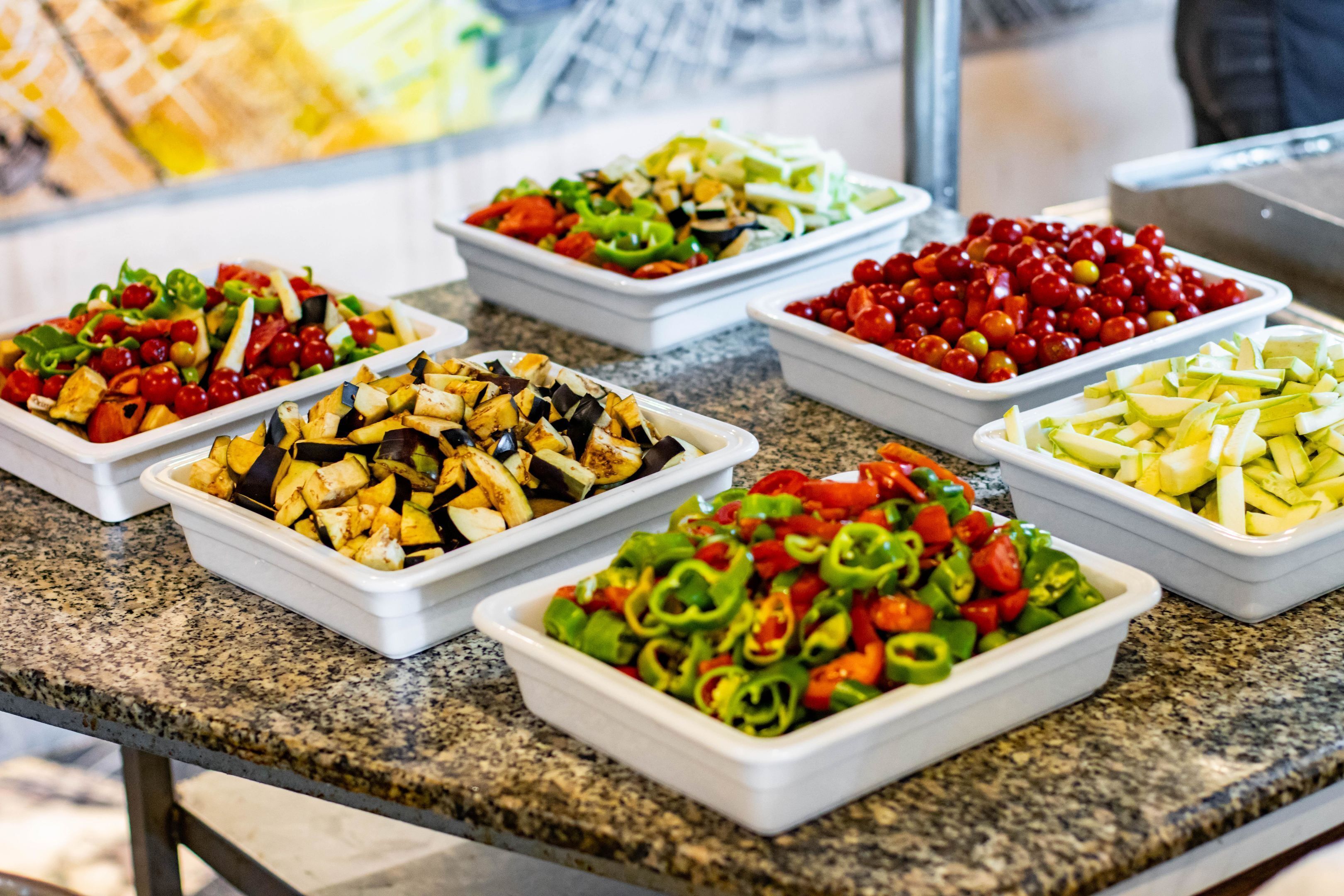 Una mesa de buffet con diversos platos, incluyendo ensaladas, frutas y verduras.