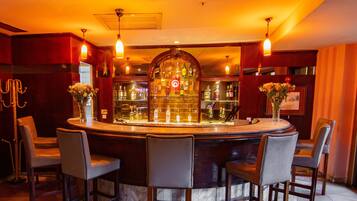 Zona de bar con barra circular, múltiples sillas y una exhibición de botellas de licor.