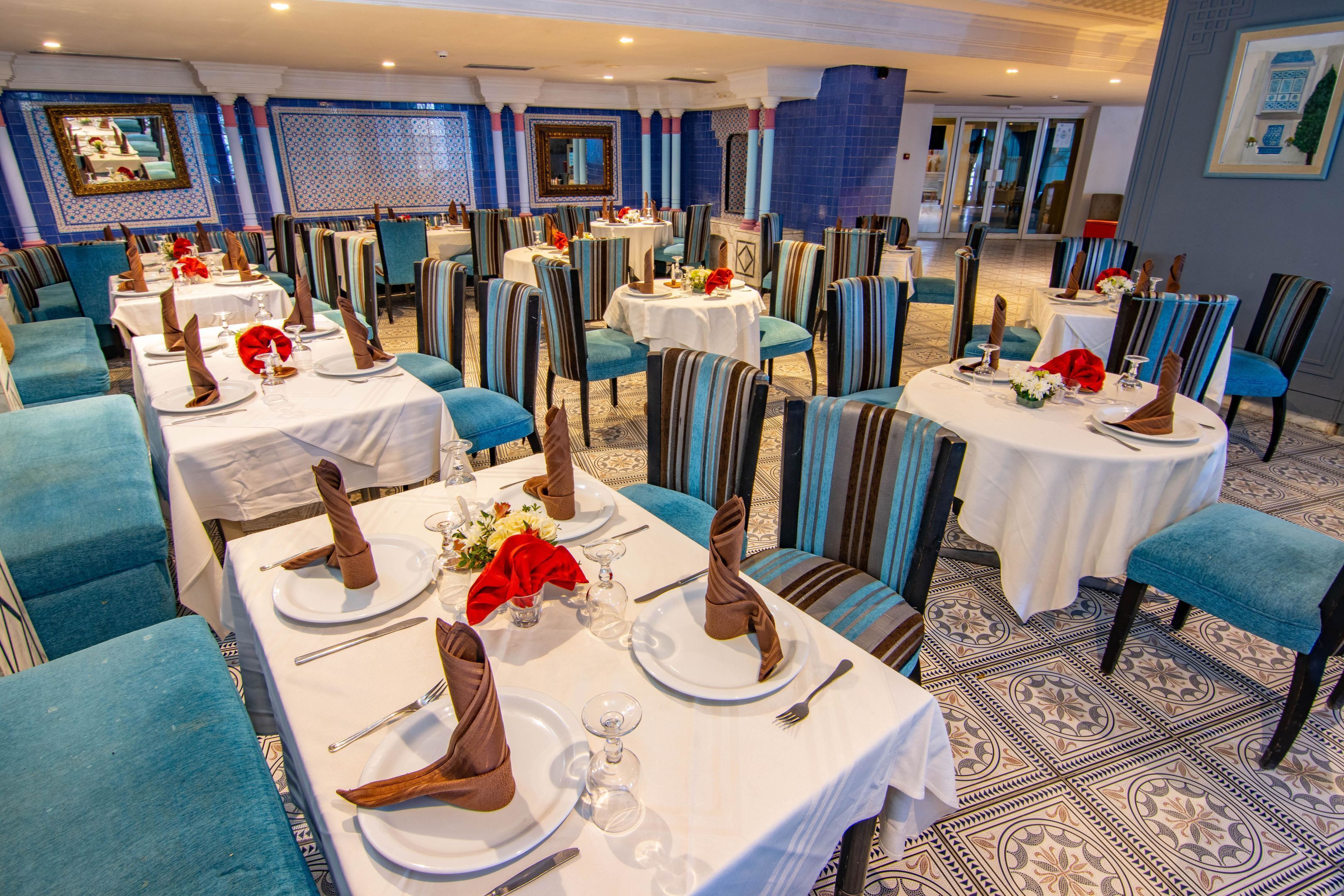 A restaurant with multiple tables set for dining, featuring striped chairs and white tablecloths.