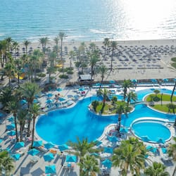Una piscina techada, una piscina al aire libre, sombrillas