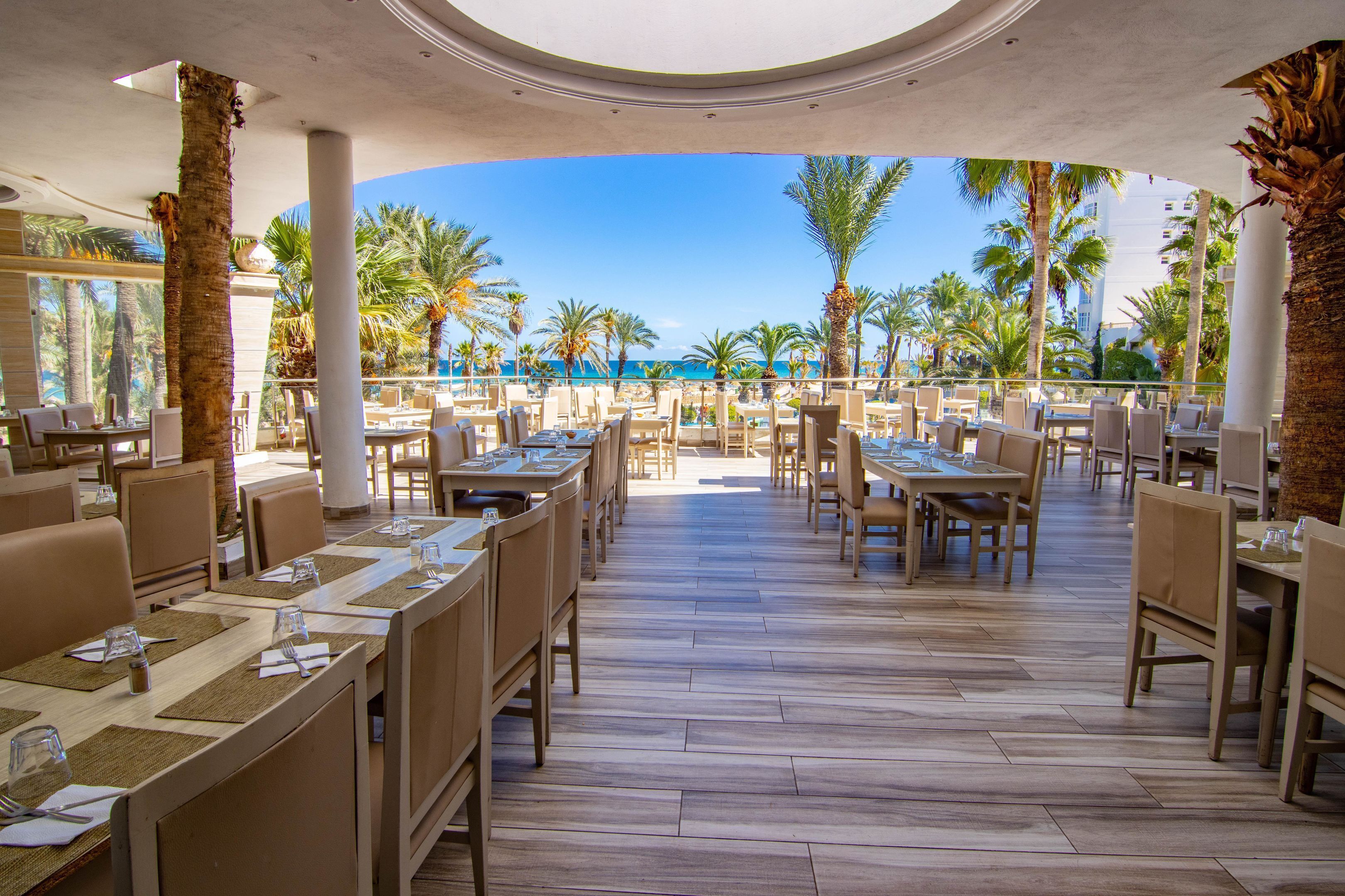 A restaurant with a view of the beach and palm trees.