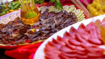 A variety of food items including a plate with sliced meat, a glass with a drink, and garnishes like lime slices and herbs.