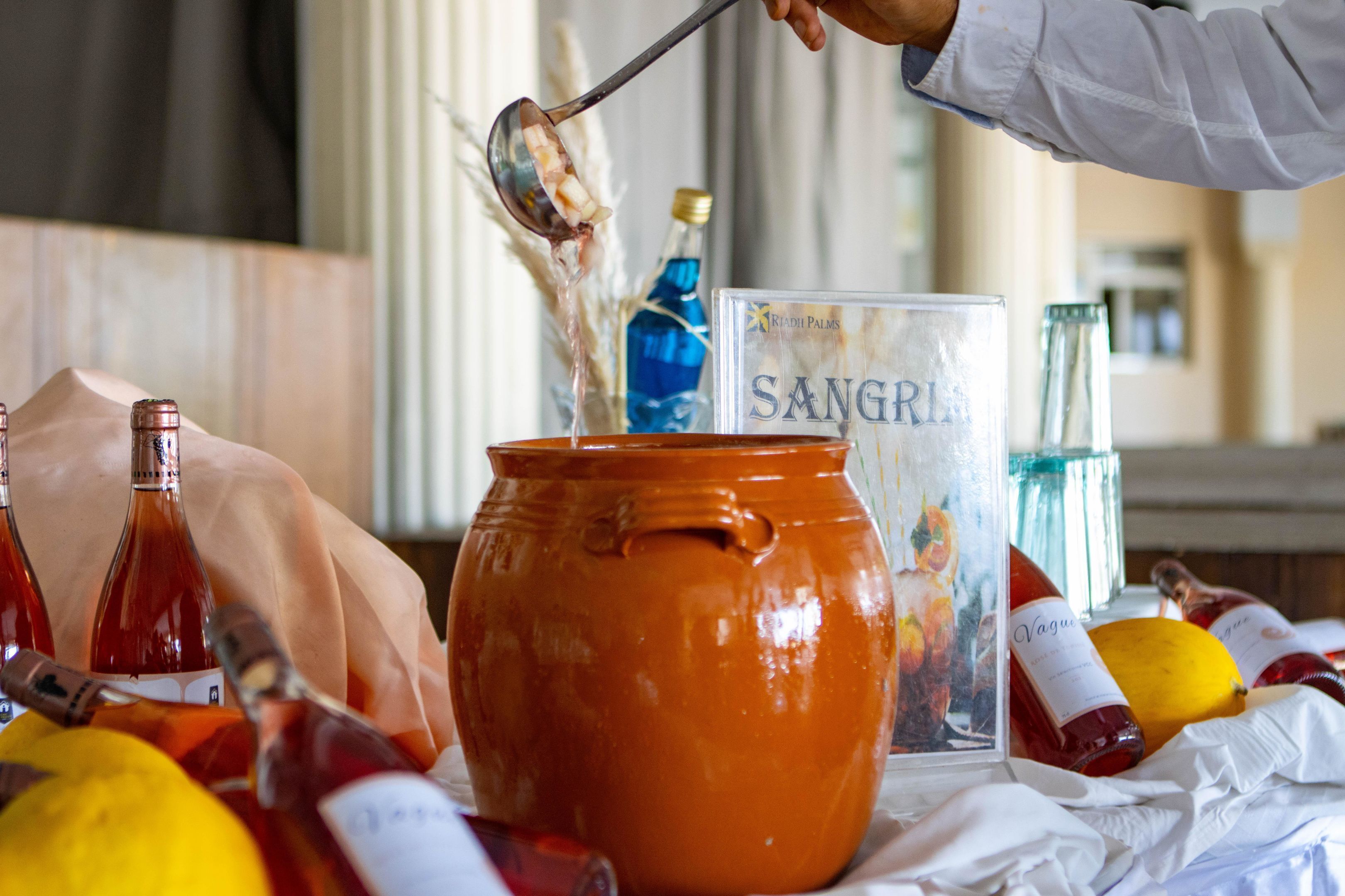 A table with various bottles and a large orange pot.
