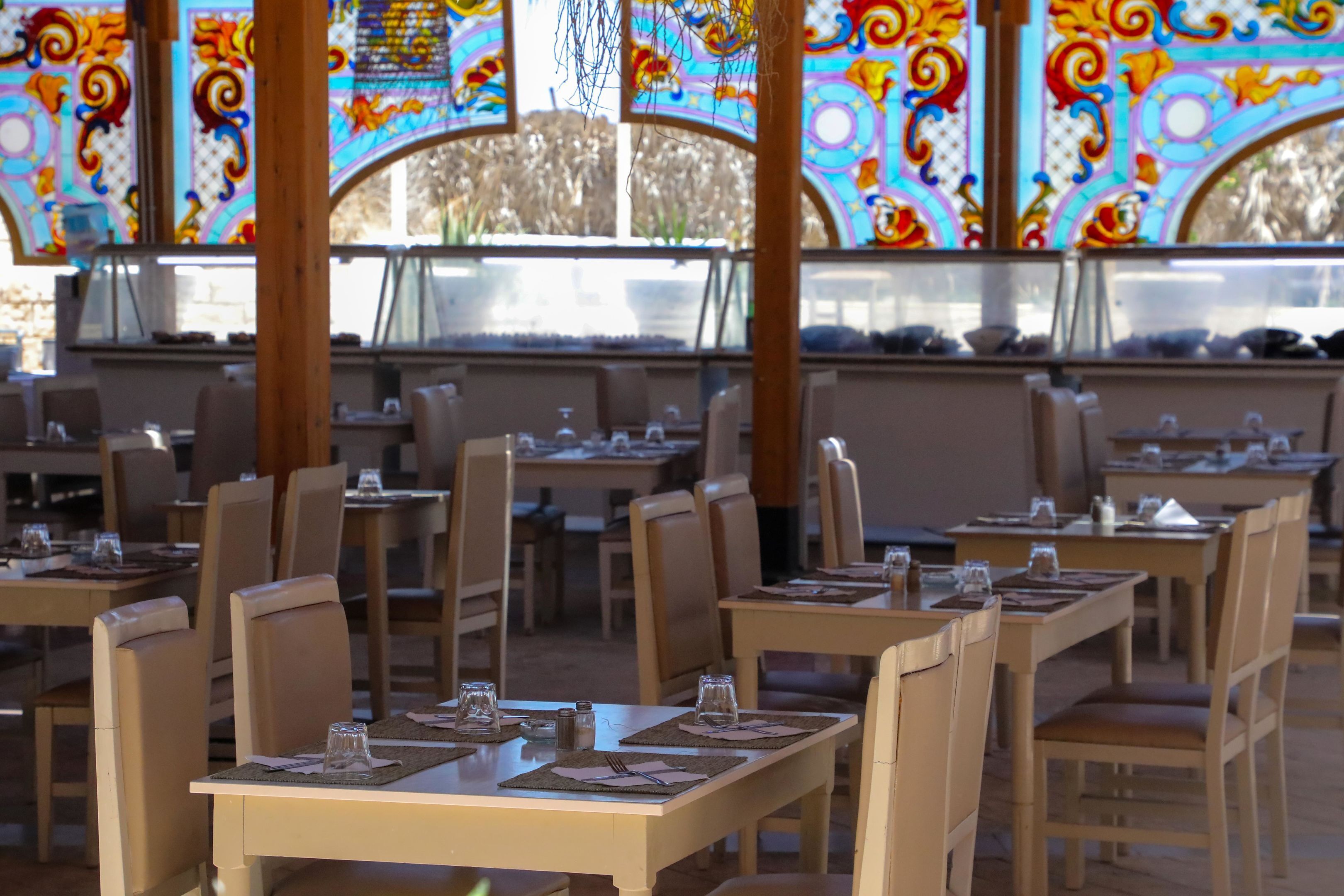 A restaurant with multiple tables and chairs, each set with cutlery and glassware.