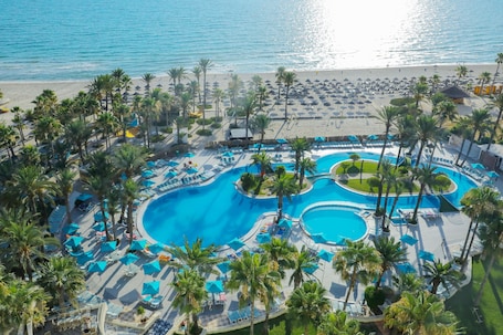 Innenpool, Außenpool, Sonnenschirme, Liegestühle. Riadh Palms Resort & Spa