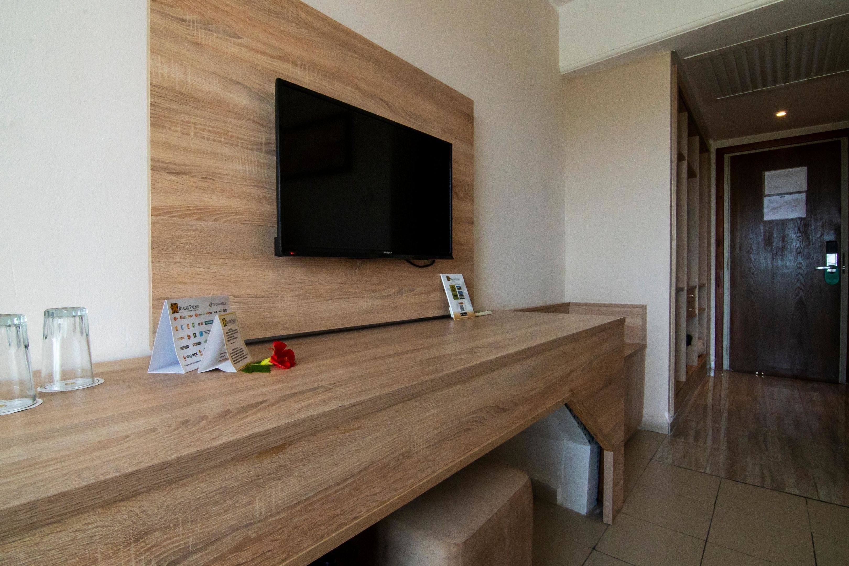 Una recepción con un televisor montado, una barra de madera y un letrero pequeño.