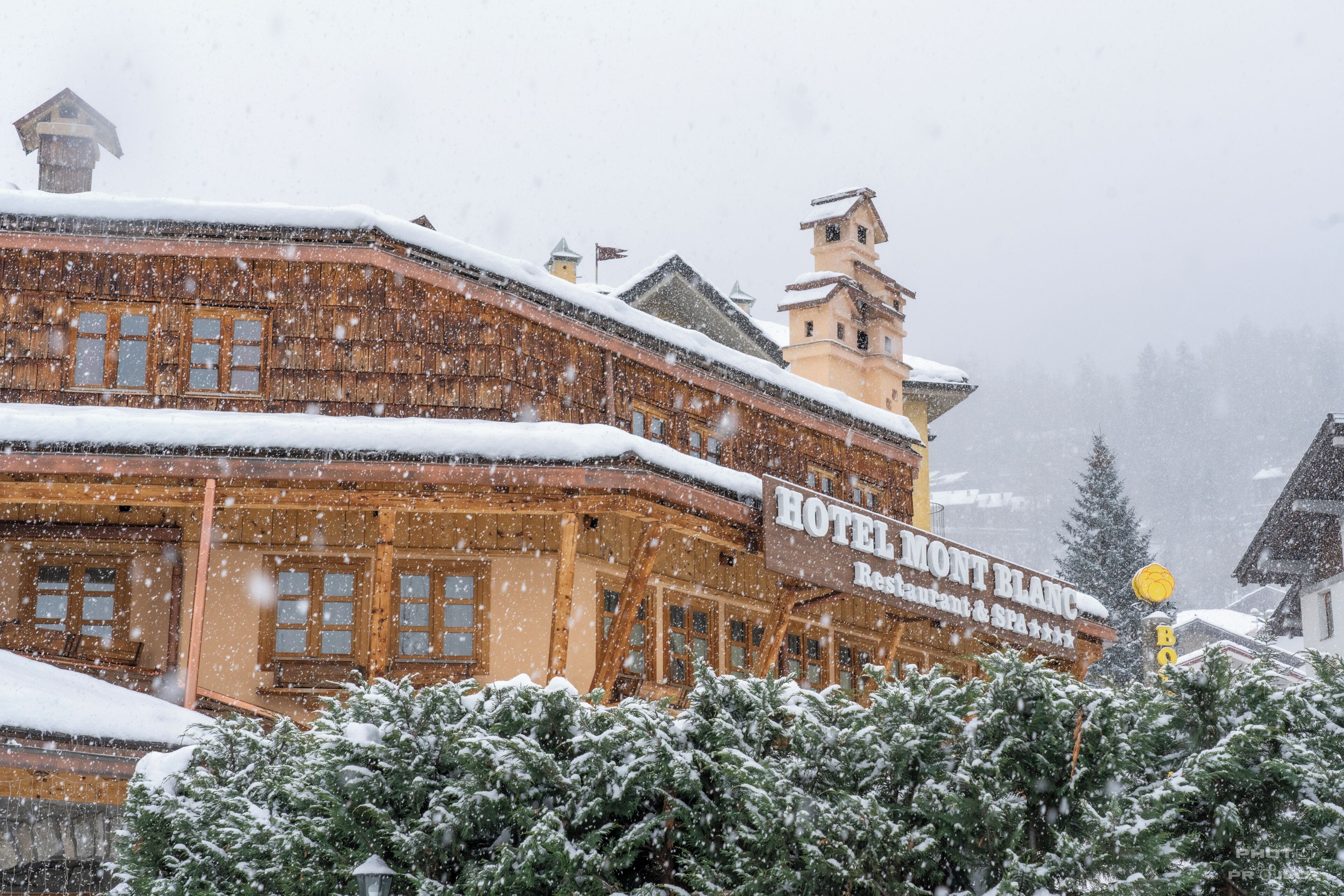 Een houten gebouw met een bord waarop 'HOTEL MONT BLANC Restaurant & SPA' staat.