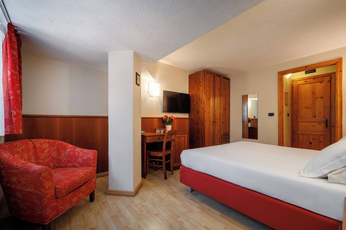A room with a bed, a desk, a chair, and a television.