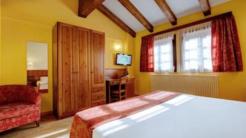 Ein Zimmer mit einem Bett, einem Holzschrank, einem Schreibtisch mit Stuhl, einem Fernseher und einem Fenster mit Vorhängen.
