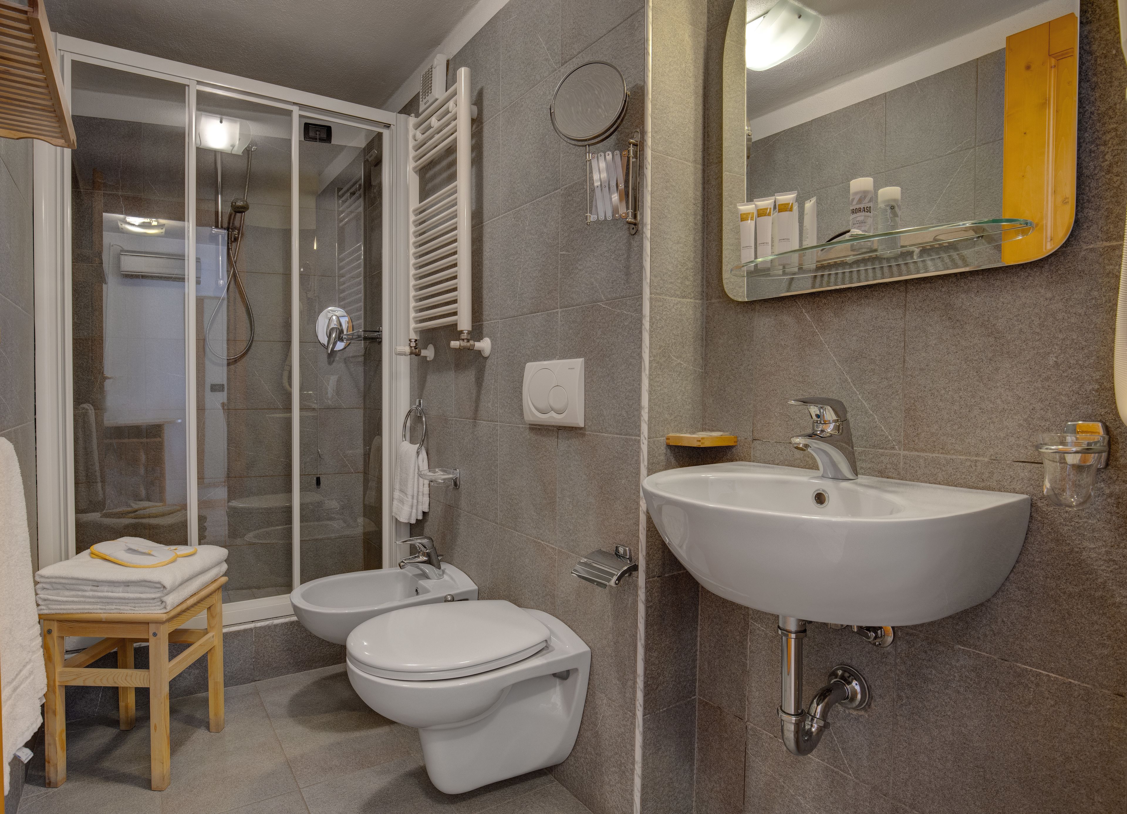 Een moderne badkamer met een douchecabine van glas, een witte wastafel en twee toiletten.
