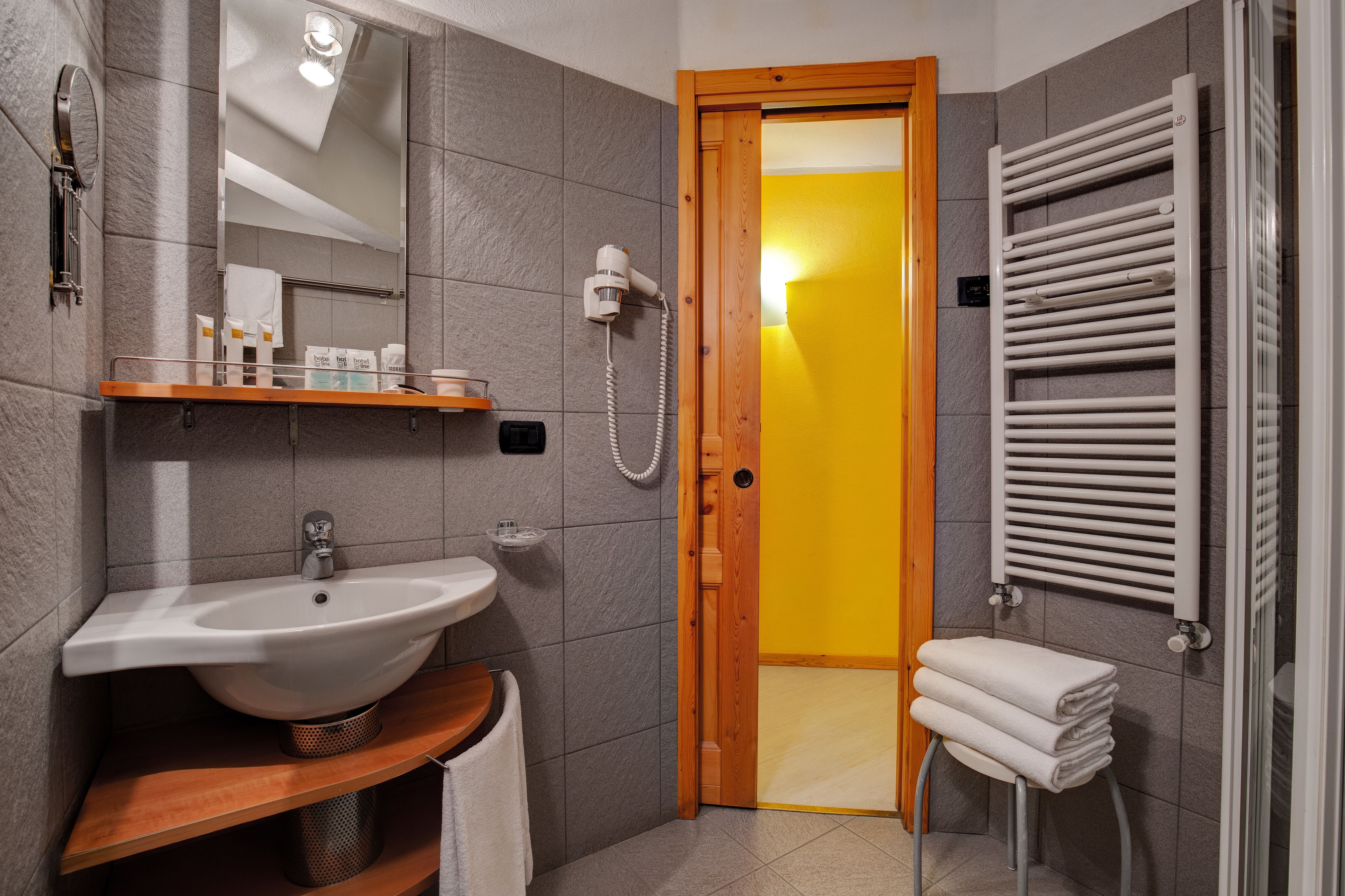 Un baño moderno con lavamanos, espejo, toallero y zona de ducha.