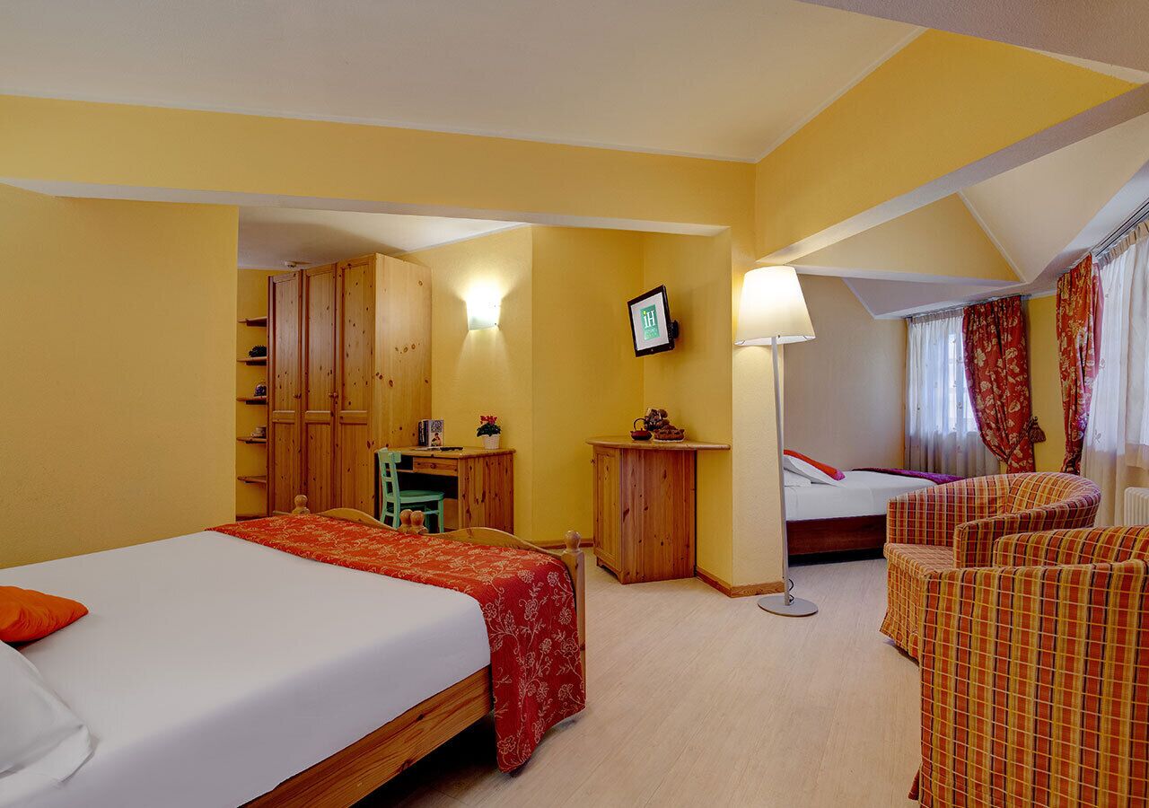 Ein Hotelzimmer mit zwei Betten, einem Schreibtisch, einem Stuhl und einem Fernseher.