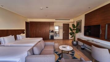 Une chambre d’hôtel avec deux lits, un canapé, une télévision, un bureau et une plante.