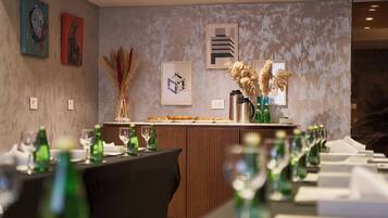 A restaurant with a long counter, green bottles, and framed artwork on the wall.