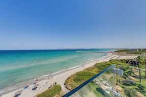 A beach with clear turquoise water, a sandy shore, and a view of distant mountains. - Playa Esperanza Resort (Muro)