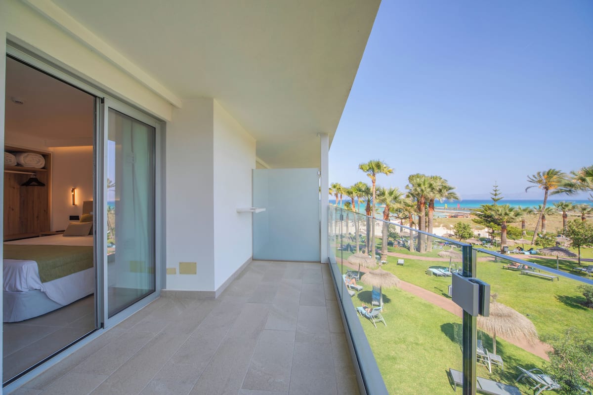 A balcony with a clear view of a beach and palm trees.