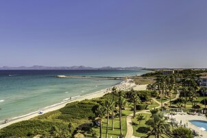 Un resort con playa, palmeras y piscina.