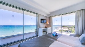 A hotel room with a large bed, a desk, a TV, and a view of the ocean. - Playa Esperanza Resort (Muro)