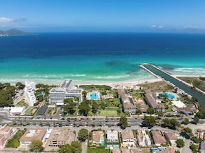 An aerial view of a coastal resort with a beachfront, a marina, and a hotel with multiple swimming pools. - Playa Esperanza Resort (Muro)
