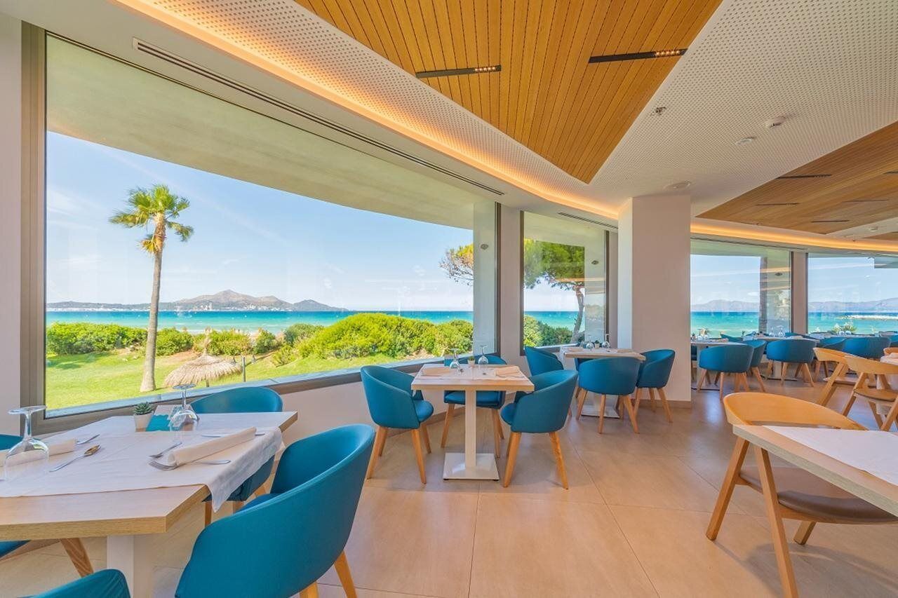 Ein Restaurant mit großen Fenstern und Meer- und Grünblick.