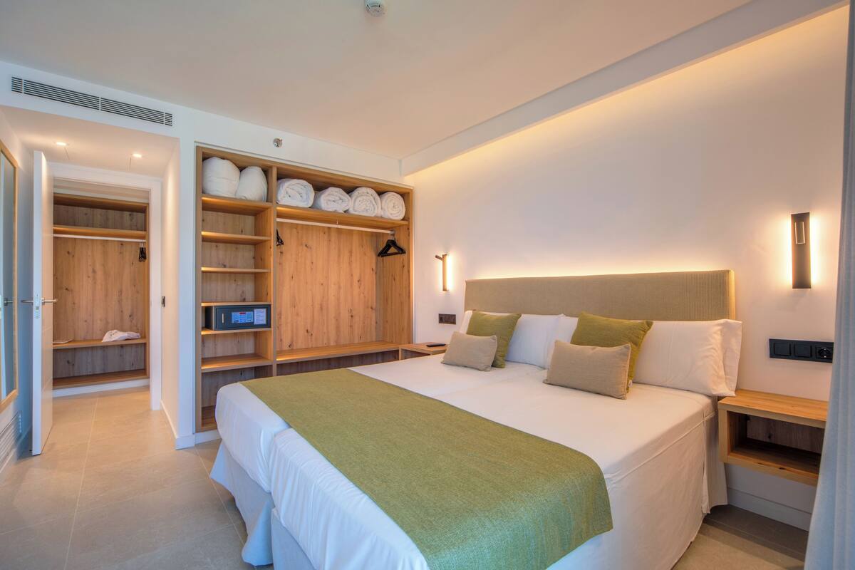 A modern bedroom with a large bed, wooden wardrobe, and built-in shelves.