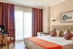 Ein Hotelzimmer mit Bett, Schreibtisch, Stuhl, Nachttisch und Lampe.