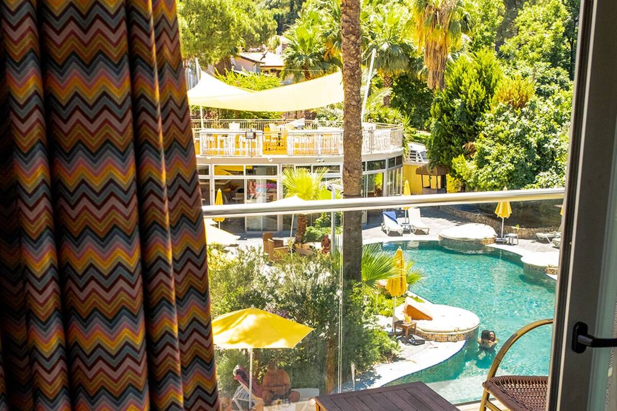 A balcony with a view of a pool, chairs, and a table.