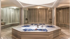 Un baño lujoso con una amplia bañera de mármol, un espejo redondo y un aplique de techo.