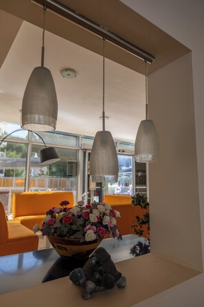 Ein modernes Interieur mit Essbereich, Tisch mit floraler Dekoration, orangefarbenen Stühlen und Pendelleuchten.