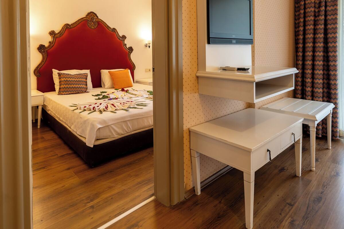 A hotel room with a bed, a TV mounted on the wall, a desk, and a chair.