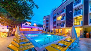 A pool area with sun loungers and a building with balconies. - Mersoy Exclusive Hotel (Marmaris)