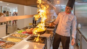 A chef performing a flambé with a wok in a buffet setting. - Mersoy Exclusive Hotel (Marmaris)