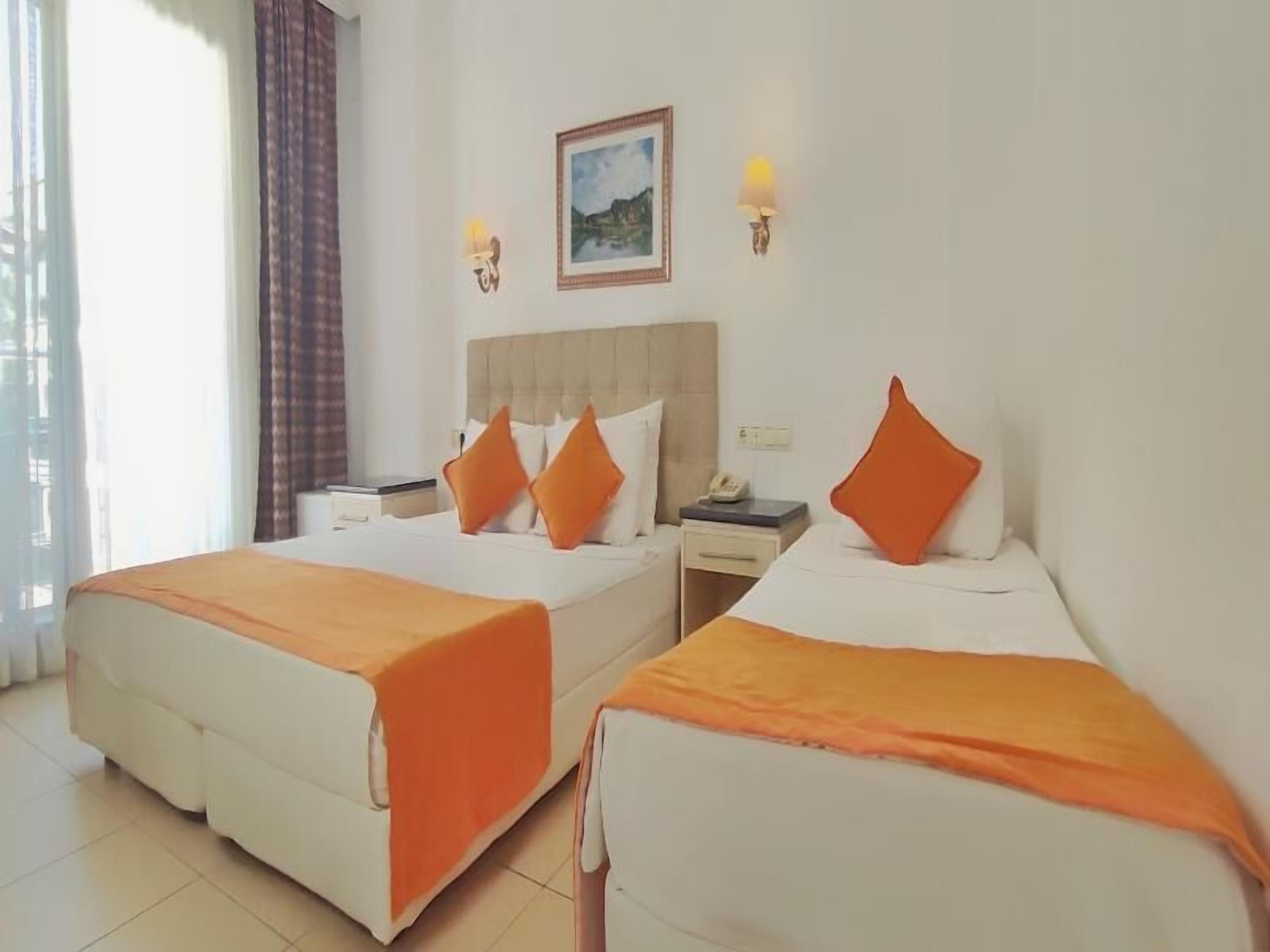 A hotel room with two beds, a nightstand, a telephone, and a painting on the wall.