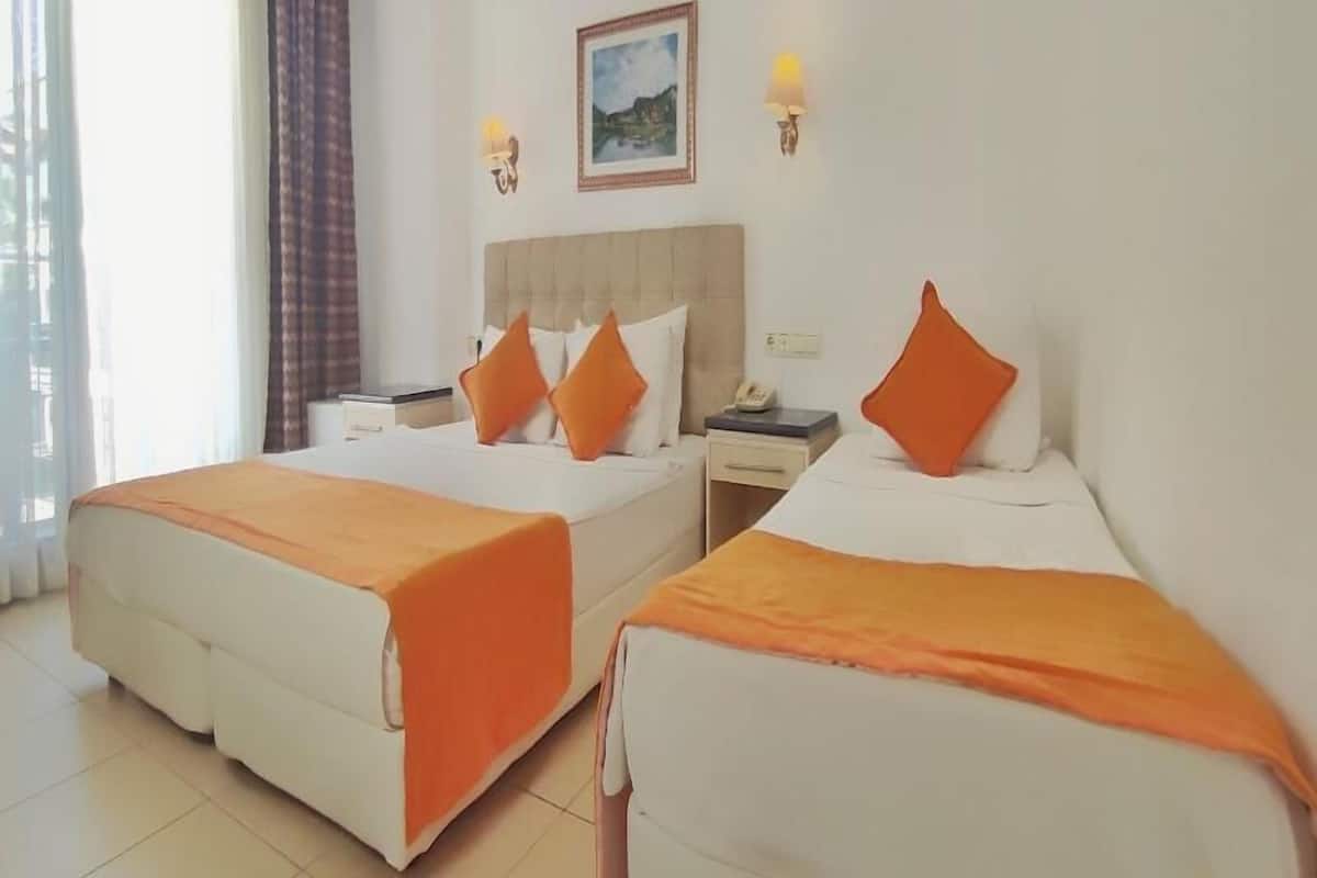 A hotel room with two beds, a nightstand, a telephone, and a painting on the wall.