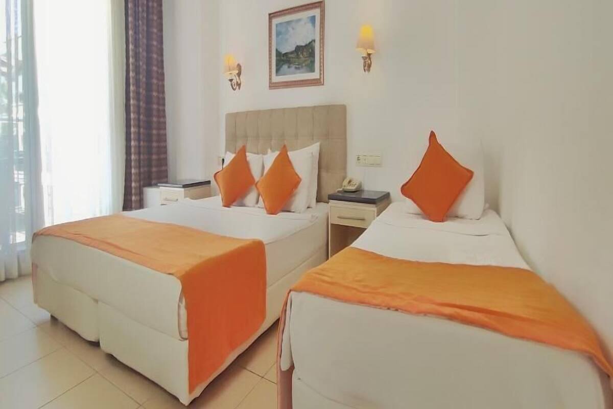 A hotel room with two beds, a nightstand, a telephone, and a painting on the wall.