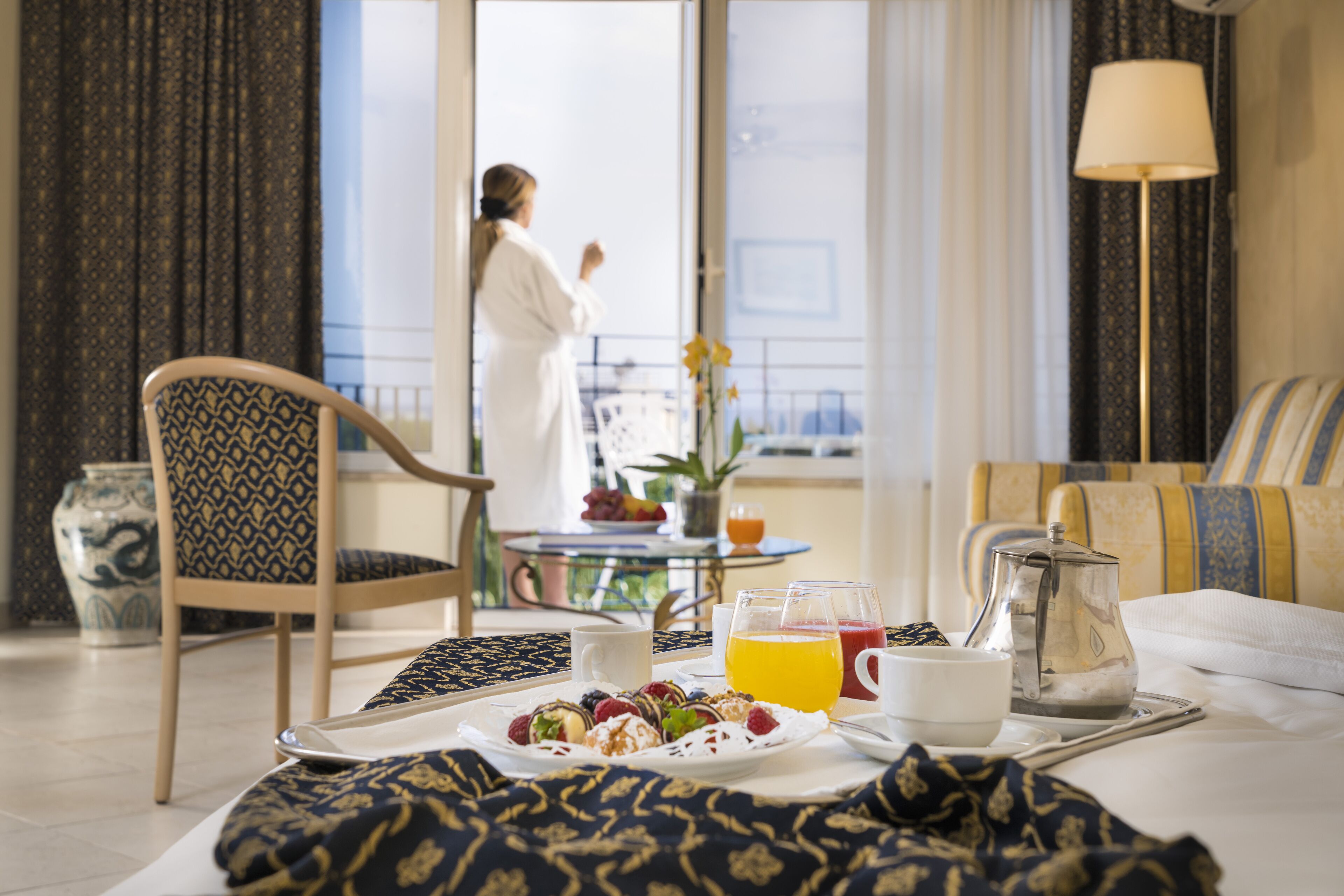 A breakfast setup with a plate of pastries, a coffee pot, and a fruit drink on a tray.
